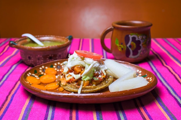 sopes acompañados de encurtidos y pieles de cerdo en un plato de barro comida tradicional mexicana