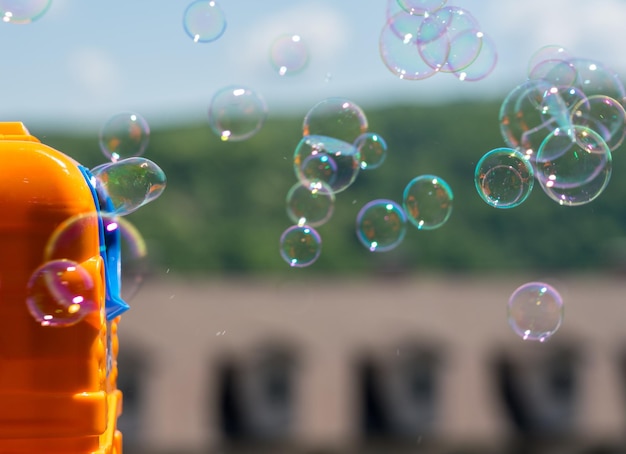 Soplador de burbujas de jabón de juguete para niños creando burbujas en un día soleado de verano