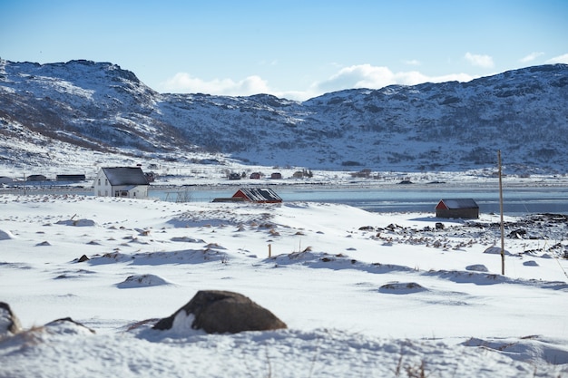 Soporte de casa de madera tradicional noruego en la orilla del fiordo y las montañas en la distancia. Islas Lofoten. Noruega. viajes mundiales