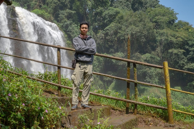 Soporte de hombre usar sudadera con capucha en frente de la gran caída de agua con carrete de mano Semarang Java central