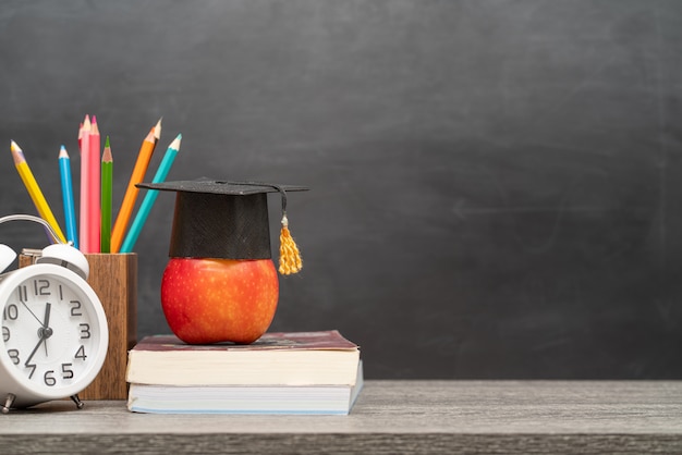 Foto soporte de manzana roja, libros y lápices en el escritorio