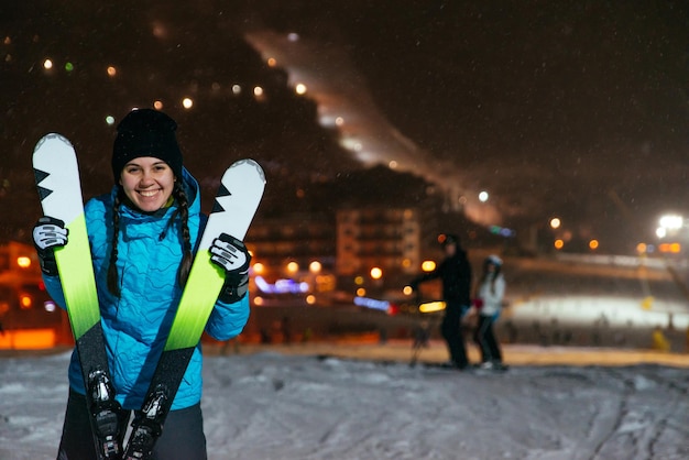 Soporte de mujer con esquí en la cima de la colina nevada