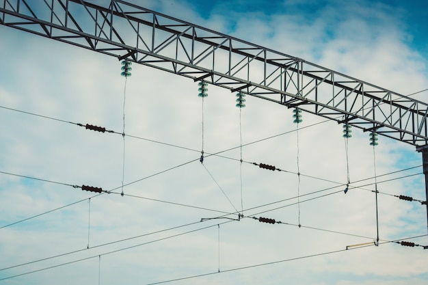 Foto soporte de primer plano de la red de ferrocarril de contacto eléctrico contra el cielo azul nublado