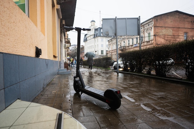 Soporte de scooter eléctrico en la calle de la ciudad de lluvia