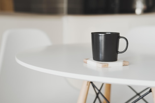 Soporte de taza de café negro vacío sobre una montaña rusa de mármol en la mesa de la cocina