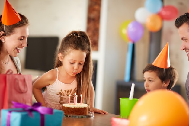 Soprando as velas enquanto faz um desejo Foto recortada de uma família comemorando um aniversário em casa
