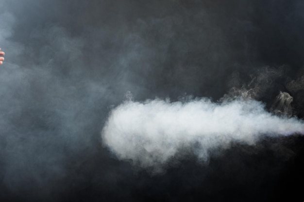 Sopros macios densos de fumaça branca e neblina sobre fundo preto, nuvens de fumaça abstratas, movimento turva fora de foco. Fumar golpes de máquina de gelo seco voa e esvoaçante no ar, textura de efeito