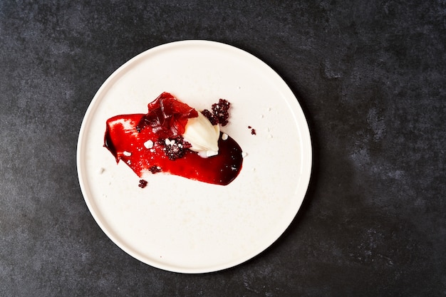 Sorbete de frambuesa en un plato blanco, primer plano. Helado de frambuesa con jarabe dulce