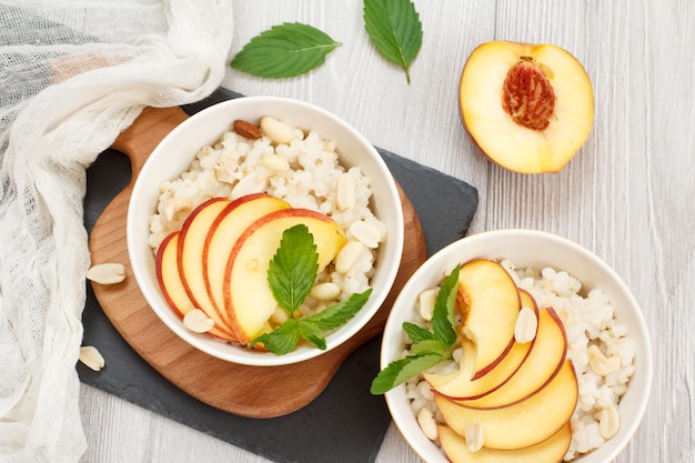 Sorghum-Porridge mit Pfirsich-Cashew-Nüssen und Mandeln in Porzellanschalen frische Pfirsiche