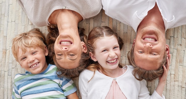 Sorglose liebevolle Eltern von oben, die sich mit ihrem niedlichen kleinen lachenden Sohn und ihrer Tochter entspannen Glückliche kaukasische vierköpfige Familie, die sich entspannt und zusammen spielt Fröhliche Kinder, die Zeit miteinander verbringen