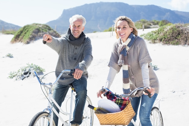 Sorglose Paare, die auf eine Fahrradfahrt und ein Picknick auf dem Strand gehen