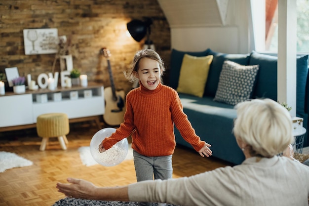 Sorgloses kleines Mädchen, das sich zu Hause mit ihrer Großmutter amüsiert