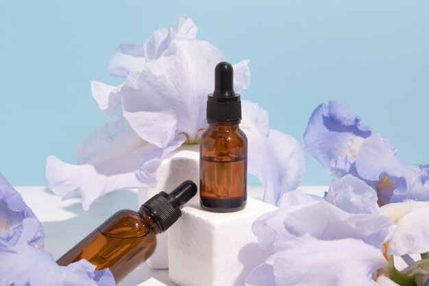 Soro com extratos florais para cuidados com a pele Cosméticos naturais em frascos de vidro com pipeta e flores de íris no pódio Conceito de spa para cuidados com o rosto e corpo