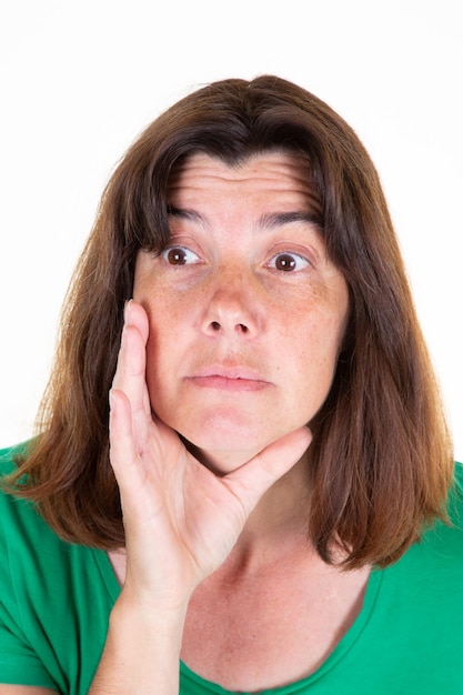 Foto sorprende a una mujer infeliz retrato de mediana edad con camisa verde y fondo blanco.