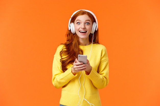 Sorprendida y asombrada, emocionada mujer pelirroja sonriente descubrió que la banda favorita lanzó una nueva canción