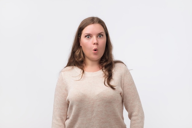 Sorprendida hermosa mujer regordeta con cabello largo y apariencia atractiva mirando con ojos grandes