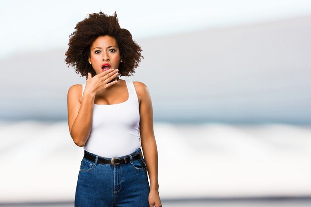 sorprendida joven mujer negra cubriendo su boca