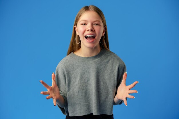 Sorprendida jovencita sorprendida contra el fondo azul en el estudio