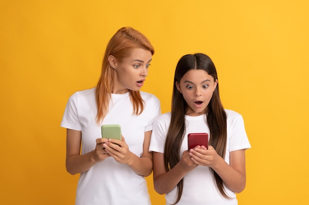 Sorprendida mamá y niña chateando en línea usando un chat de teléfono inteligente moderno