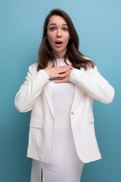 sorprendida mujer morena joven en vestido sobre fondo azul