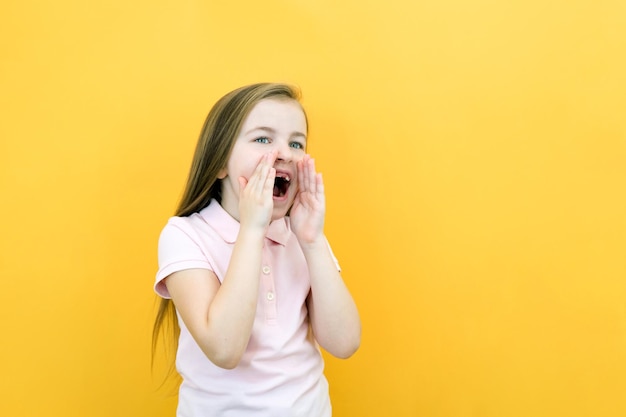 Sorprendida niña feliz mirando el espacio de la copia encantada Expresión expresiva Presento un producto Hermosa niña gritando aislada en amarillo