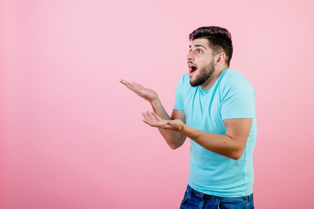 Sorprendido chico del Medio Oriente señalando con la mano a copyspace y gritando