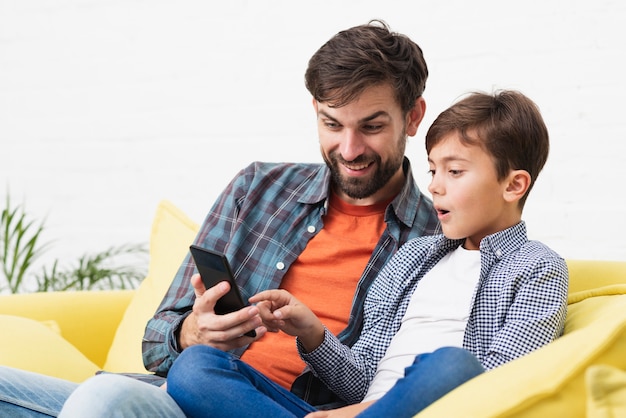 Sorprendido hijo y padre mirando por teléfono