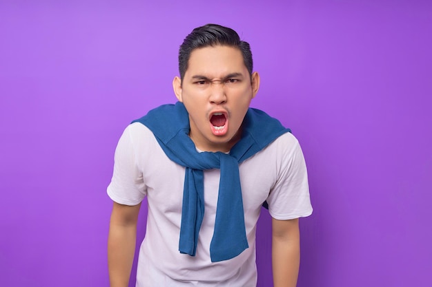 Sorprendido joven asiático vestido con camiseta blanca mira la cámara con la boca abierta dice wow aislado sobre el concepto de estilo de vida de la gente de fondo púrpura