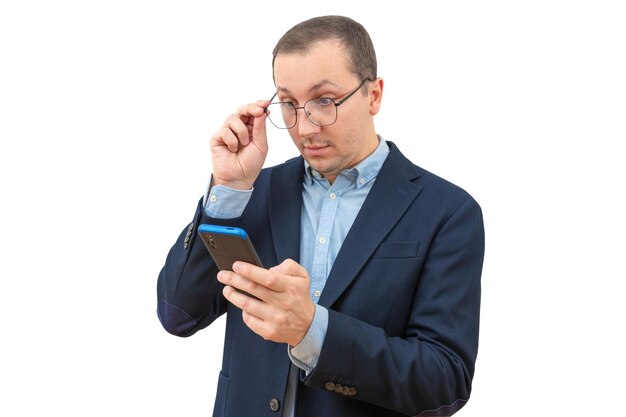 Sorprendido joven empresario sosteniendo teléfono mirando teléfono móvil leyendo noticias sobre fondo blanco.