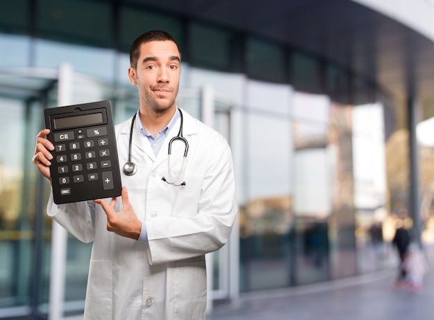 Sorprendido joven médico con una calculadora