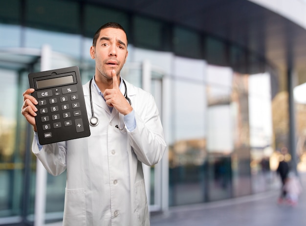 Sorprendido joven médico con una calculadora