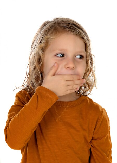 Sorprendido niño rubio con ojos azules cubriendo su boca.