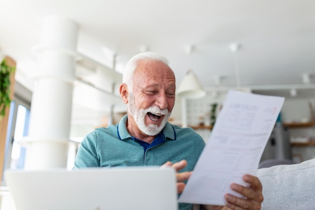 Sorprendido, riendo, feliz, viejo, maduro, jubilado, mirando a través de documentos en papel, sintiéndose emocionado, analizando información financiera, obteniendo reembolso de impuestos o aprobación de préstamos bancarios en casa