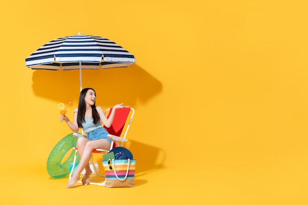 Foto sorprendió hermosa mujer asiática sentada en la silla de playa