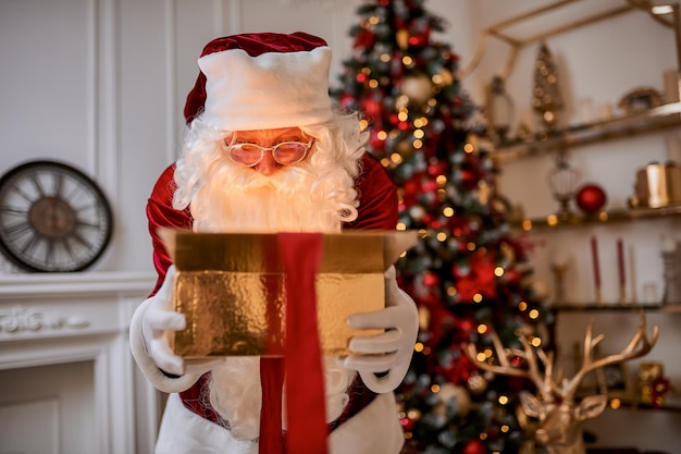 Sorprendió a Santa Claus con un regalo mágico y brillante cerca del hermoso árbol de Navidad. Año nuevo y Feliz Navidad, concepto de felices fiestas