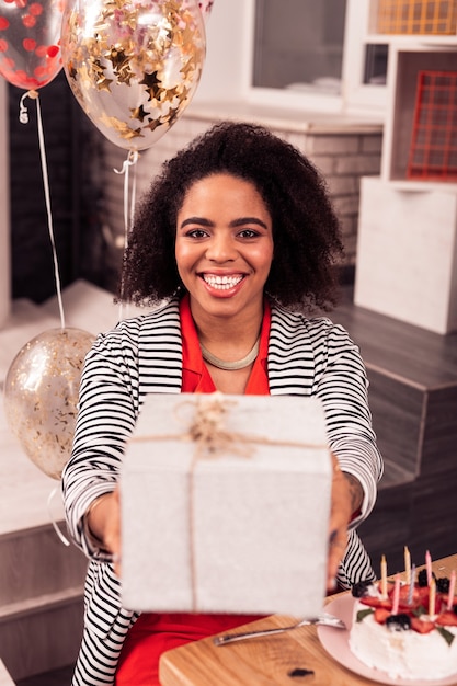 Sorpresa asombrosa. Bonita mujer alegre tomando su regalo de cumpleaños mientras está de buen humor