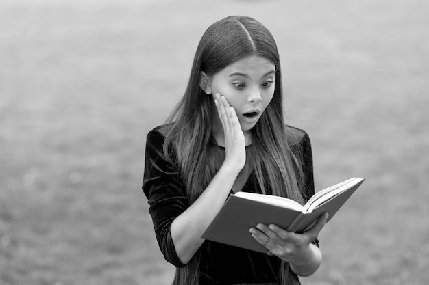 La sorpresa ayuda a estudiar cosas nuevas El niño sorprendido lee el libro de estudio al aire libre Conocimiento e información Biblioteca escolar Educación en lectura Motivación e interés Atraer la atención de los alumnos