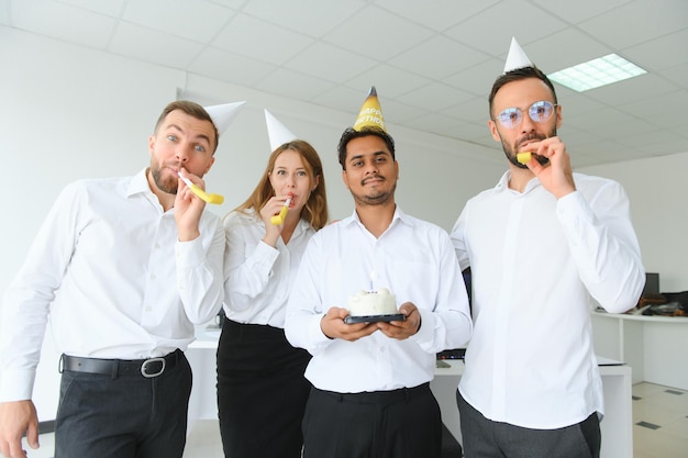 Sorpresa gente feliz de raza mixta celebrando el cumpleaños de un colega en la oficina moderna