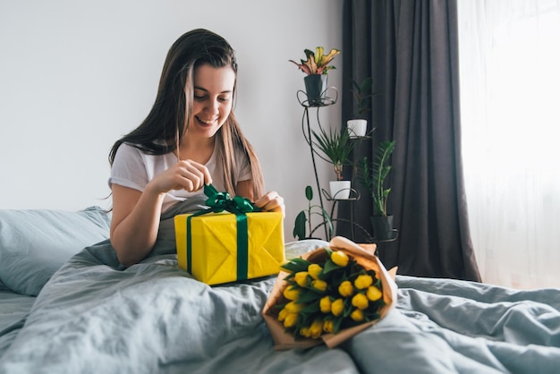 Foto sorpresa por la mañana flores con caja de regalos en la cama