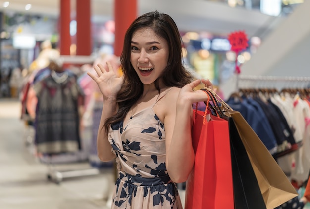 Sorpresa mujer con bolsas de compras en tienda de ropa.