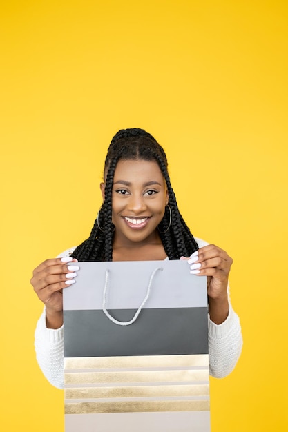 Sorpresa navideña Descuento de compras de viernes negro Alegre mujer africana sosteniendo una bolsa de maqueta de marca aislada en el fondo naranja del espacio libre