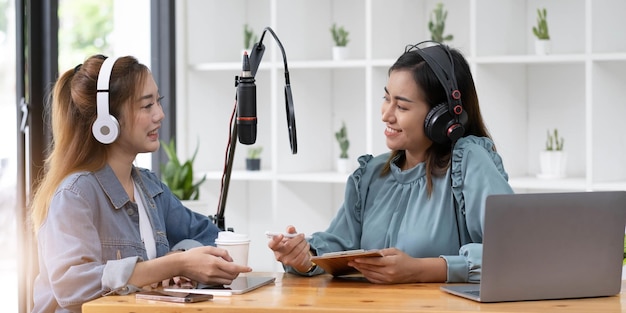 Sorria dois apresentadores de rádio de homem jovem asiático no microfone de fones de ouvido enquanto conversam conversa gravando podcast em transmissão no estúdio juntos Tecnologia de fazer o conceito de áudio de registro