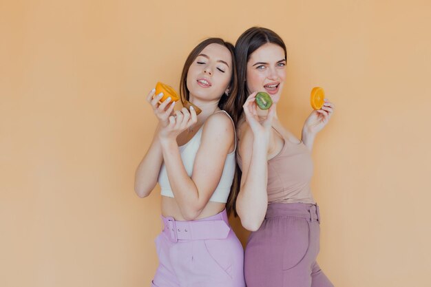 sorria meninas vestindo roupas de verão, elas estão se divertindo e brincando com frutas suculentas