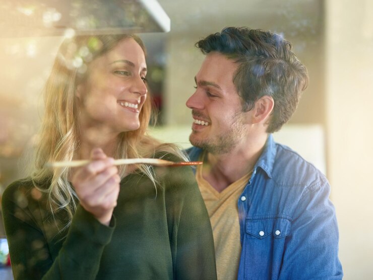 Foto sorria mulher e casal provando comida na cozinha em casa cozinhando juntos comemorar ou aniversário com uma refeição saudável homem feliz e amor para o jantar com nutrição dieta e ligação para o bem-estar