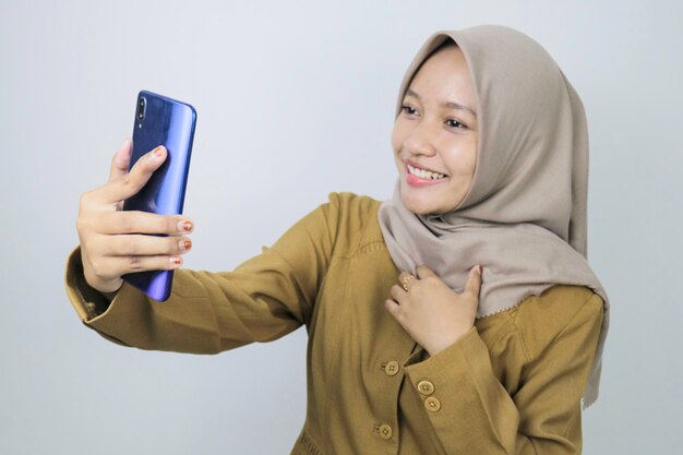 Sorria para mulheres trabalhadoras do governo ao fazer uma chamada de vídeo usando um smartphone PNS usando uniforme cáqui