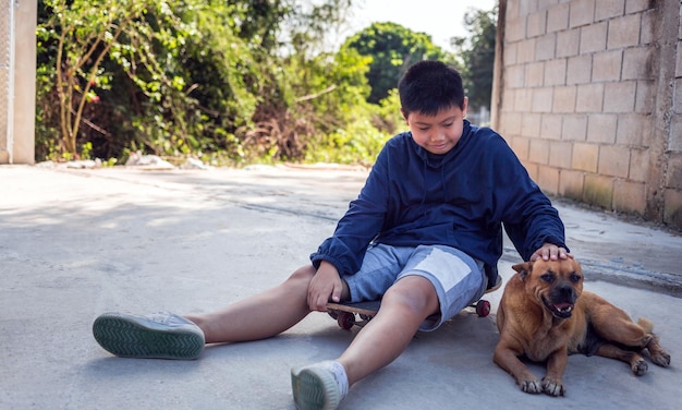 Sorria um menino asiático sentado em um skate Retrato ao ar livre de um adorável garoto asiático