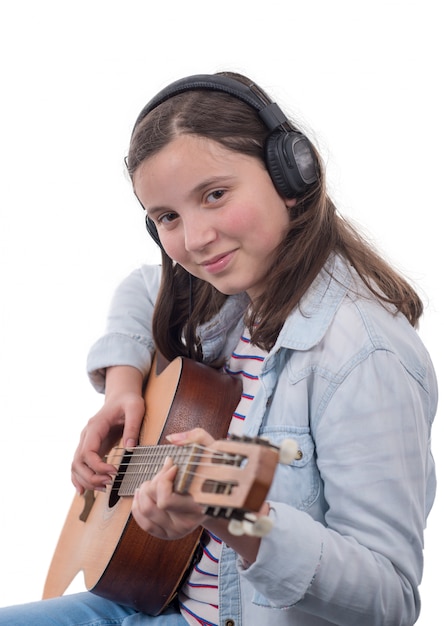 Sorridente adolescente com fones de ouvido, tocando guitarra em branco