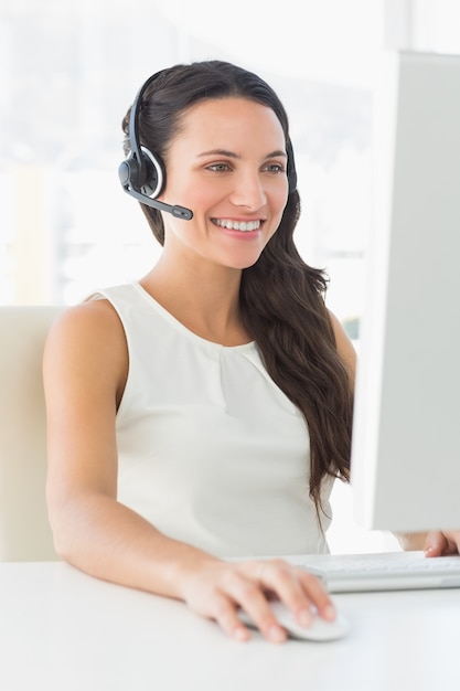 Sorridente agente de call center sentado em sua mesa em uma chamada