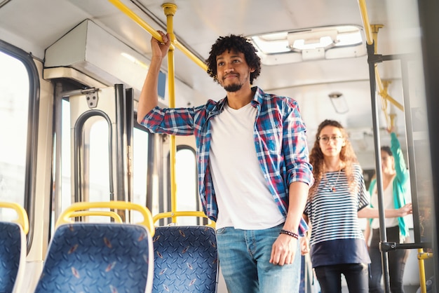 Sorridente cara afro-americana em pé no ônibus.