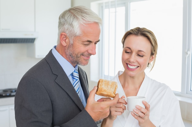 Sorridente casal com café da manhã antes do trabalho